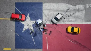 Gen4-graphicTexasflagwithcaraccidents | V.Valenzuela Law | V.Valenzuela Law Aerial view of a multi-car crash on a color-blocked road, with a red car on the left, a blue car center, a white car nearby, and a yellow car on the red section; two people stand near the blue car amid scattered debris.